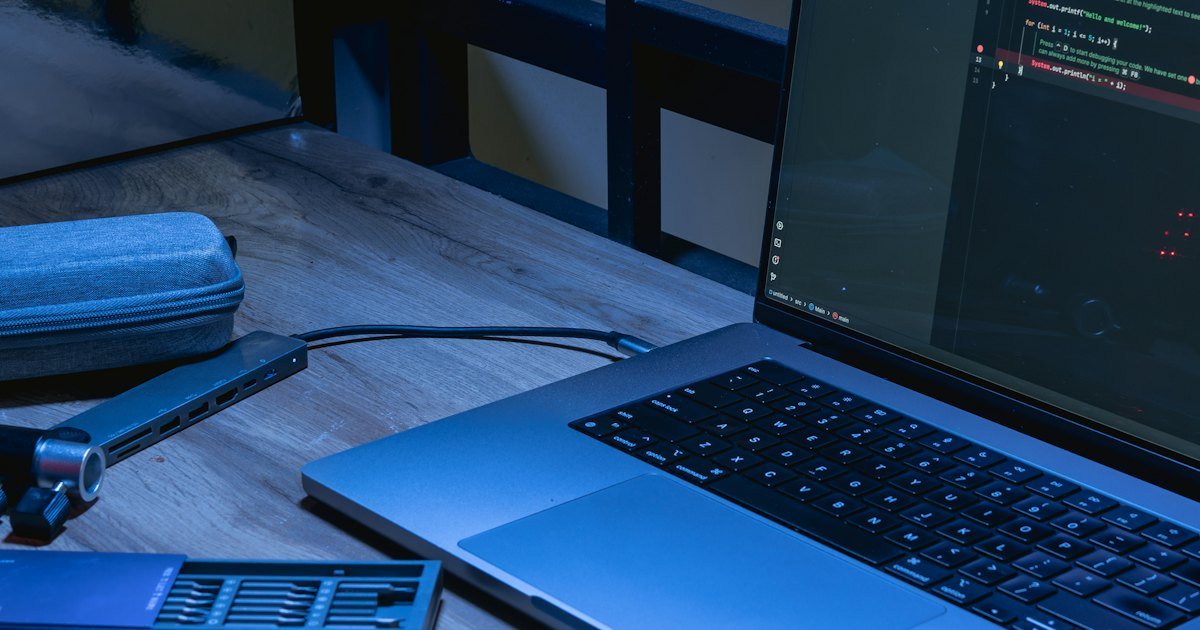 Laptop and phone on a desk with coding software open